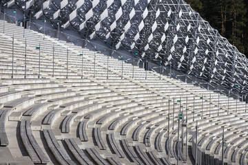 Obraz premium An empty, wooden-seated amphitheater with concrete structures and an unusual geometric screen.