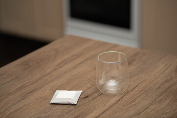 Drip coffee setup on wooden table with sugar packet beside transparent glass