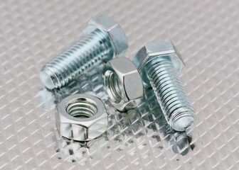 Detailed close-up of metal bolts and nuts on a reflective surface showcasing industrial hardware
