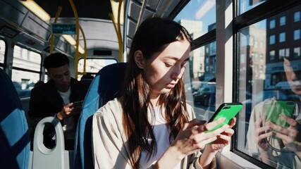 Young woman hold use green screen phone sitting in bus touch telephone public communication vertical smartphone adult finger chroma urban cellphone application digital scrolling slow motion - Powered by Adobe