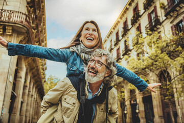 Happy senior couple having fun walking on city street - Two older tourists enjoying together weekend summer vacation - Life style, tourism and romance moments concept