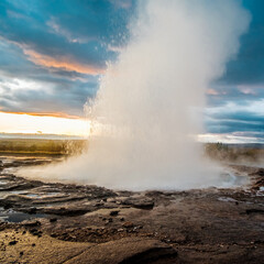 Strokkur geysir erupting with hot water and steam at sunrise in south Iceland...