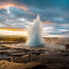 Strokkur geysir erupting with hot water and steam at sunrise in south Iceland...