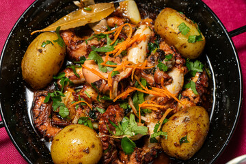 Traditional Portuguese dish, Polvo à Lagareiro, served in a rustic restaurant setting. Grilled octopus with potatoes, garlic, and olive oil, embodying authentic Mediterranean flavors. © Jmanita