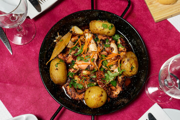 Traditional Portuguese dish, Polvo à Lagareiro, served in a rustic restaurant setting. Grilled octopus with potatoes, garlic, and olive oil, embodying authentic Mediterranean flavors.