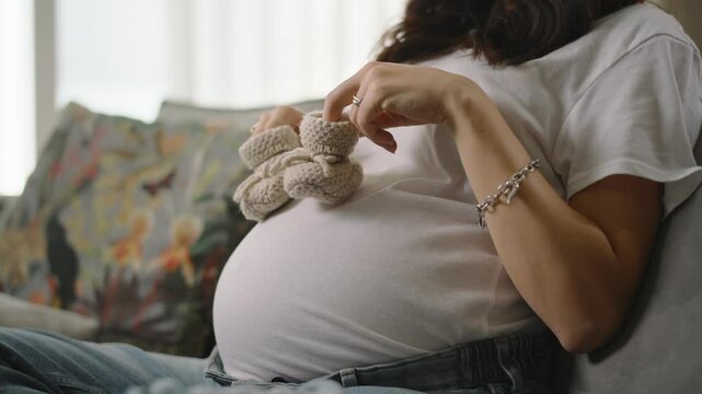 Expecting mother lovingly holding tiny baby booties on her pregnant belly, capturing the joy and anticipation of impending motherhood and the beautiful journey of pregnancy