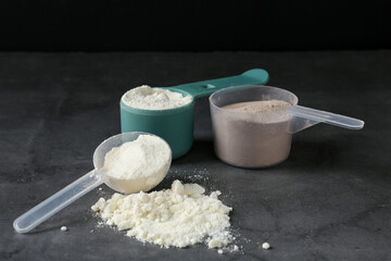 Protein powders in scoops on grey textured table