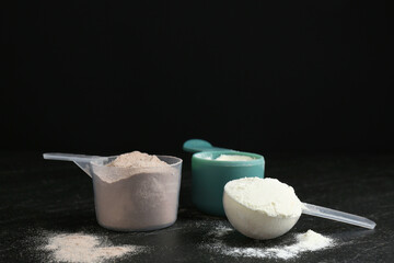 Protein powders in scoops on dark textured table