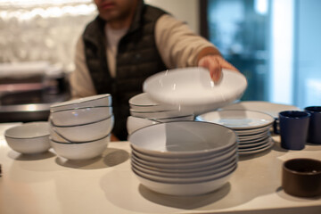 Waiter arranging white plates and bowls on a restaurant table, preparing for customers, russian cuisine