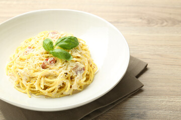 Delicious pasta Carbonara in bowl on wooden table, closeup