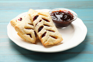 Delicious puff pastries and jam on light blue wooden table, closeup