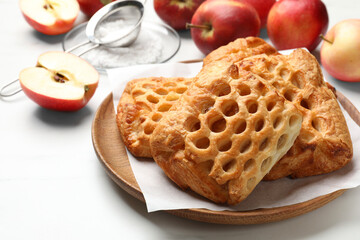 Delicious puff pastries, apples and powdered sugar on white table, closeup