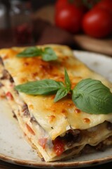 Delicious cooked lasagna with basil on plate, closeup