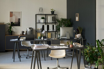 Workplaces of financial analysts with computers, lamps and stacks of financial paper documents on desks in spacious office
