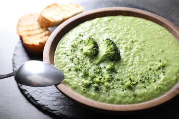 Delicious broccoli cream soup served on grey table, closeup