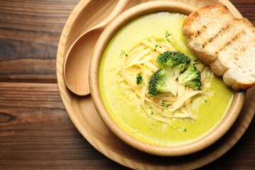 Delicious broccoli cream soup served on wooden table, top view