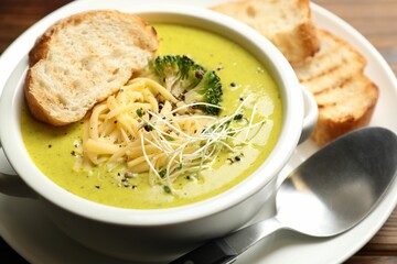 Delicious broccoli cream soup served on table, closeup