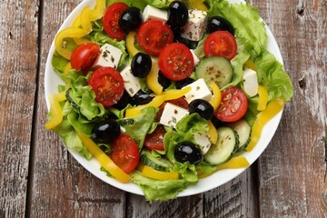 Delicious fresh Greek salad on wooden table, top view