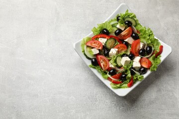 Delicious fresh Greek salad on grey table, top view. Space for text