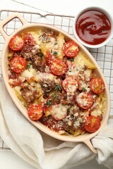 Delicious pasta casserole with cheese, tomatoes, minced meat and ketchup on white table, flat lay