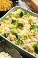 Uncooked pasta casserole in baking dish and ingredients on table, closeup