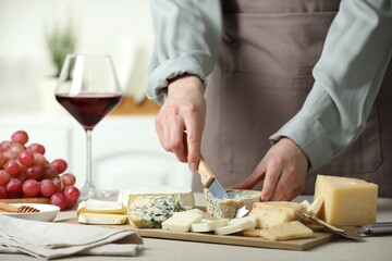 Woman slicing delicious cheese at light textured table indoors, closeup