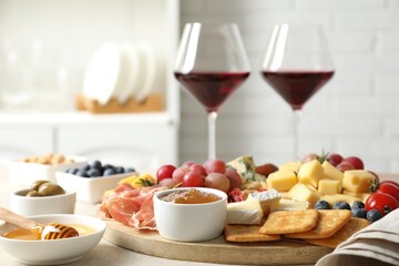 Different types of delicious cheese, other snacks and wine on light grey table, closeup