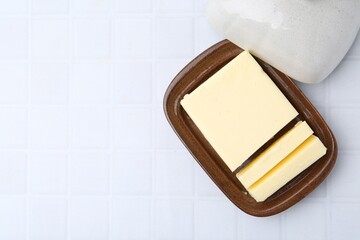 Cut tasty butter in dish on white tiled table, top view. Space for text