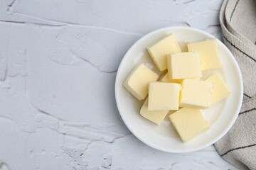 Pieces of fresh butter on white textured table, top view. Space for text