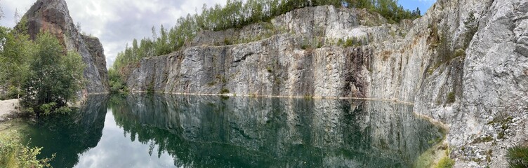Edsele Gruva. ​​A historic iron mine in Sweden, located in the Ångermanland region. Beautiful, calm blue-green water surrounded by large rock formations and trees.