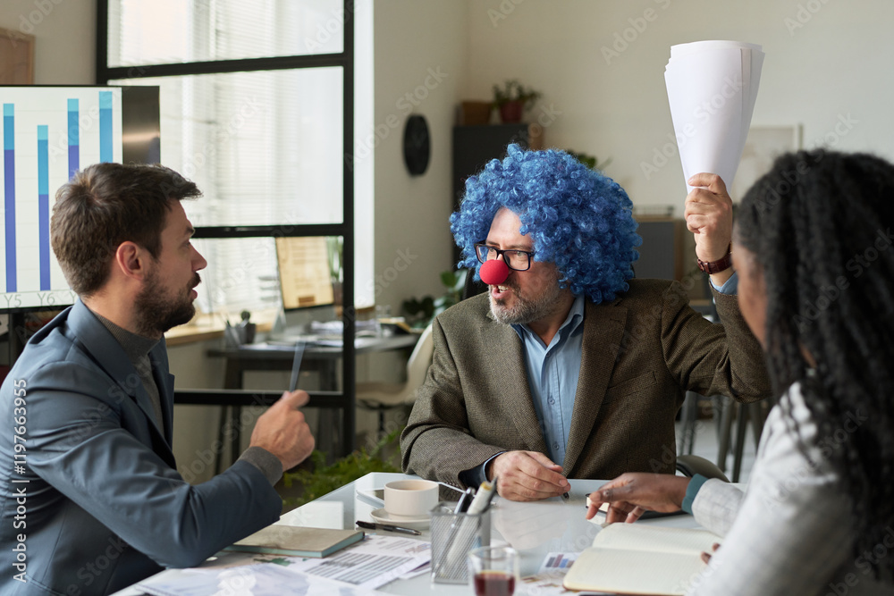 Aufkleber Angry mature boss in formalwear, clown wig and nose expressing irritation while sitting in front of two subordinates and speaking to one of them