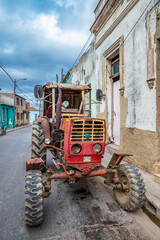 old, rusty red tractor parked on a street