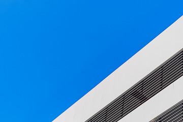 The exterior of the building is light gray with black solar metal blinds against a clear cloudless blue sky with an empty copy space. Design solutions for the design of the exterior of skyscrapers