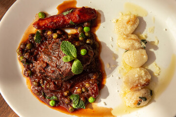 Plato de carne guisada con verduras y ñoquis