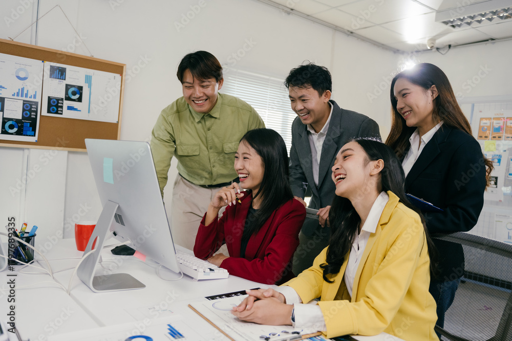 Poster Group of happy and joyful asian businesspeople laughing together while working and collaborating on a desktop computer in a modern office, enjoying teamwork and success