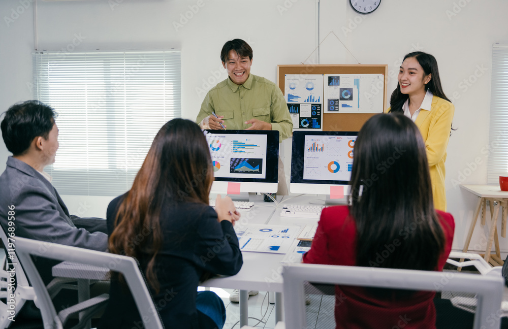 Poster Asian businesspeople engaging in a discussion about marketing strategy, utilizing charts and graphs displayed on a computer screen during a collaborative meeting in a modern office setting