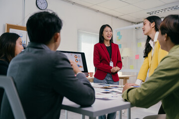 Asian businesswoman leading a meeting, sharing a presentation with her team in the office, discussing marketing strategies and data analysis, fostering collaboration and teamwork