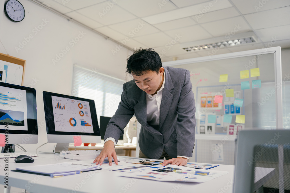 Poster young professional checking diagrams and reports on desk, using computers to develop marketing strat