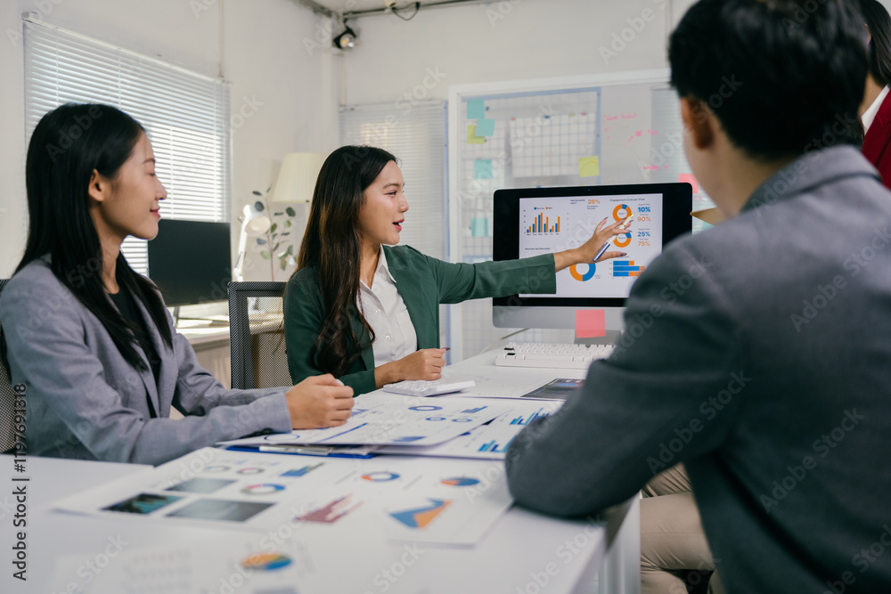 Poster asian businesswoman pointing at computer screen showing positive growth data to colleagues during a 