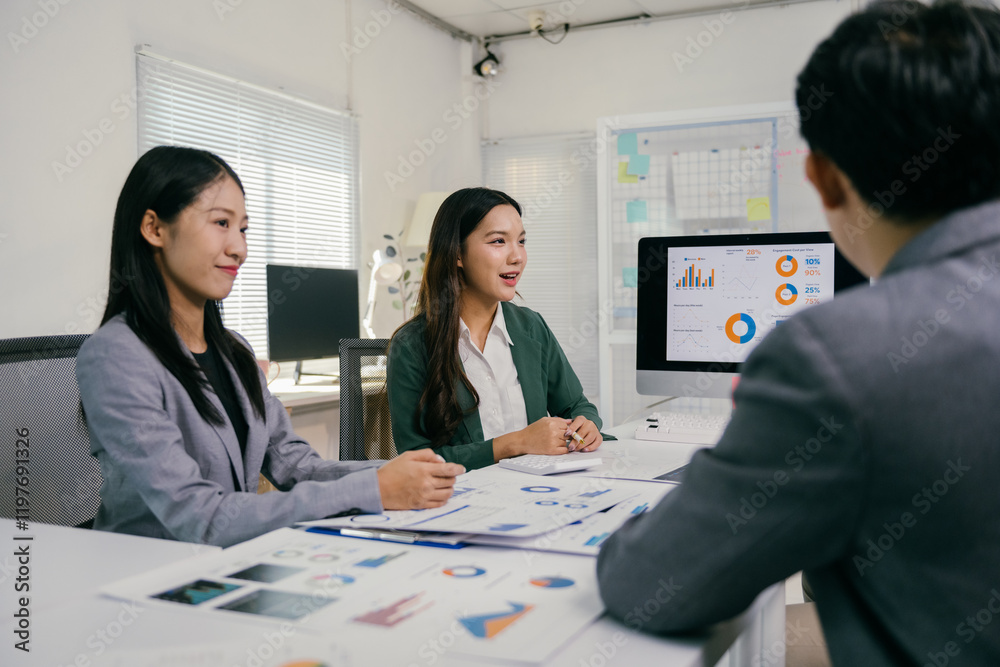 Poster asian businesswomen engaging in a discussion about marketing strategy while analyzing charts display
