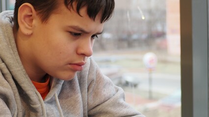 Smiling teenage gen Z boy 13-18 year old drinking coffee and holding mobile phone sitting in cafe....
