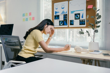 Stressed asian businesswoman with headache working on laptop in office, looking tired and sad, deep...