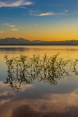 Landscape of mountains and lake at sunset and clouds reflected in the water.