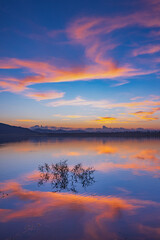 Landscape of mountains and lake at sunset and clouds reflected in the water.