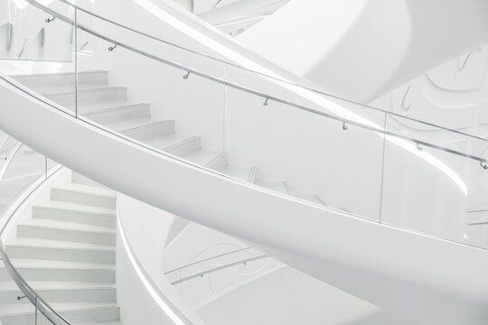 Minimalistic white spiral staircase with smooth curves and geometric patterns in The Museum of the Future, bottom view. Modern interior design in Dubai city, United Arab Emirates