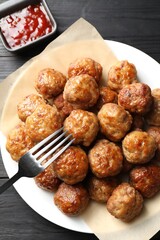 Many delicious meatballs served with ketchup on dark wooden table, flat lay