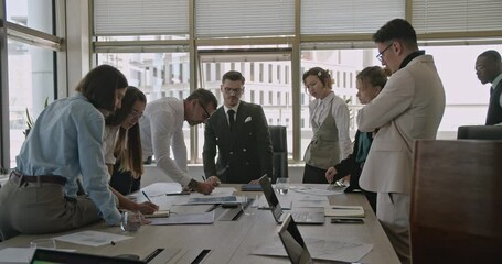 Diverse colleagues collaborate on a project during a business meeting, reviewing documents and discussing strategies in a modern office.