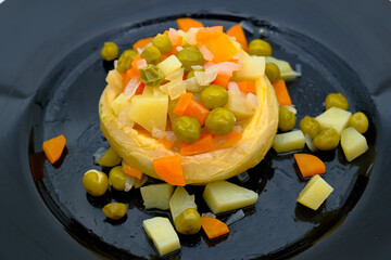 Traditional artichoke dish with potatoes and peas served in a black plate