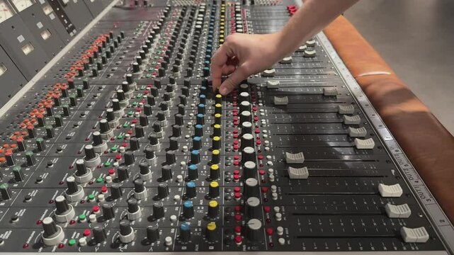 Hand using switch and knob on audio mixer
