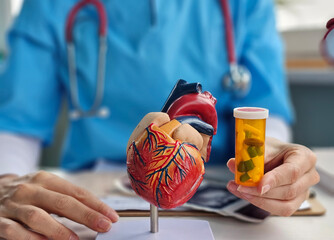 Doctor hand in holds red heart symbol and heart pills